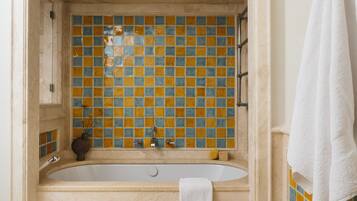 A bathroom with a bathtub, tiled walls, and a towel hanging on the wall.