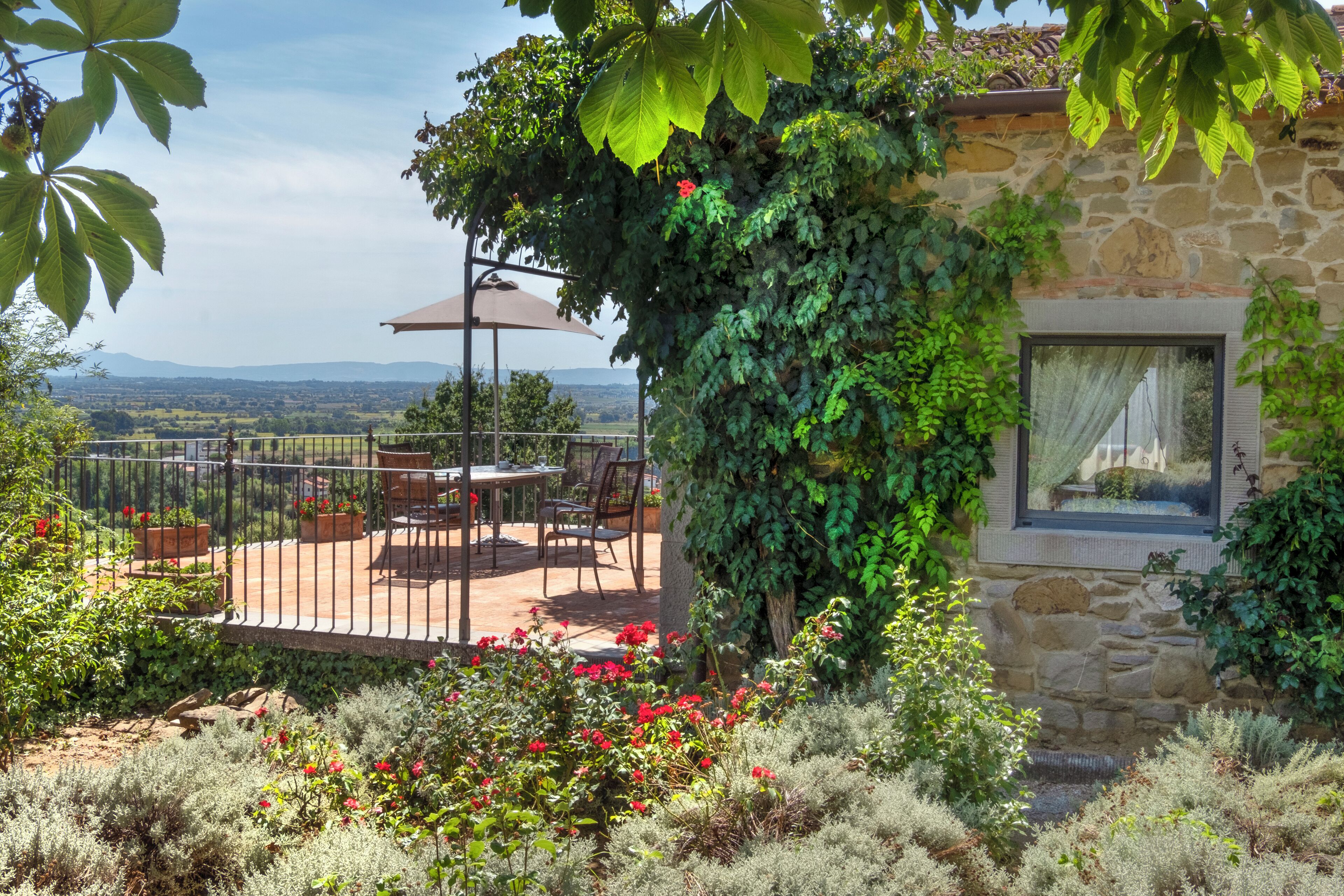 A stone building with a patio area featuring outdoor furniture and a pergola.