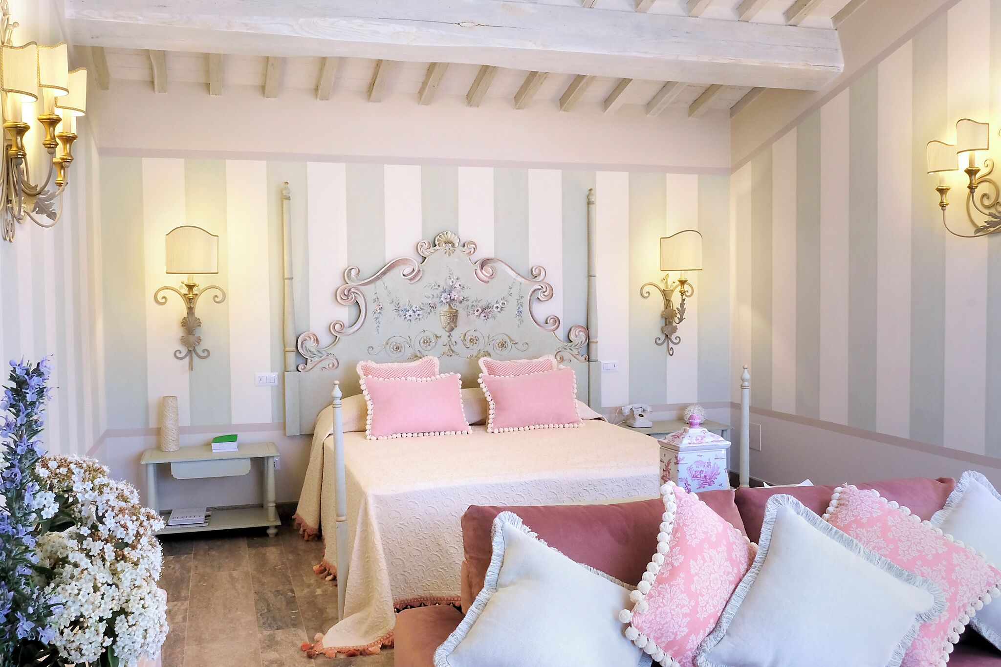Une chambre avec un grand lit, des murs à rayures et des lampes fixées au mur.