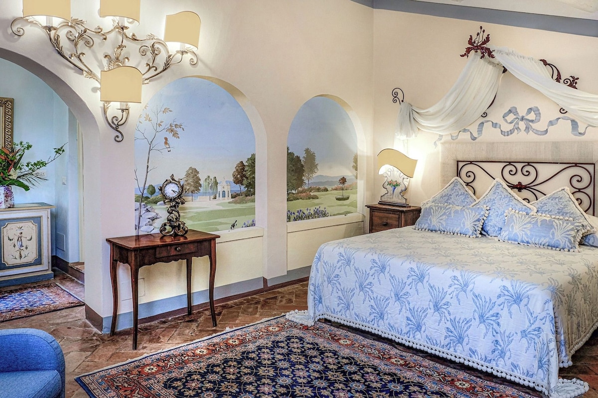 A bedroom with a bed, a nightstand, a wall-mounted clock, and a decorative lamp.