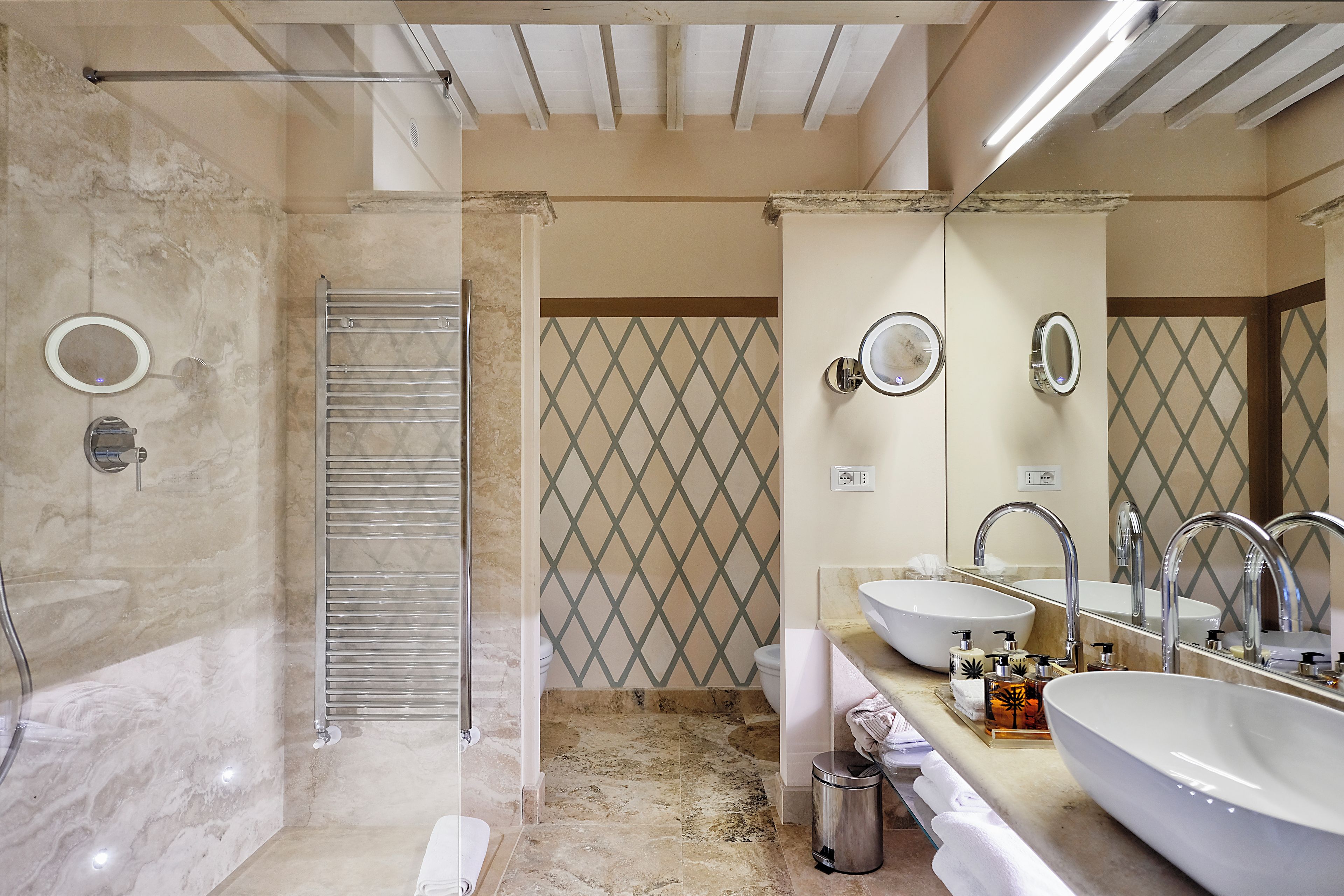 Une salle de bain moderne avec une douche à l’italienne, deux vasques et un grand miroir.