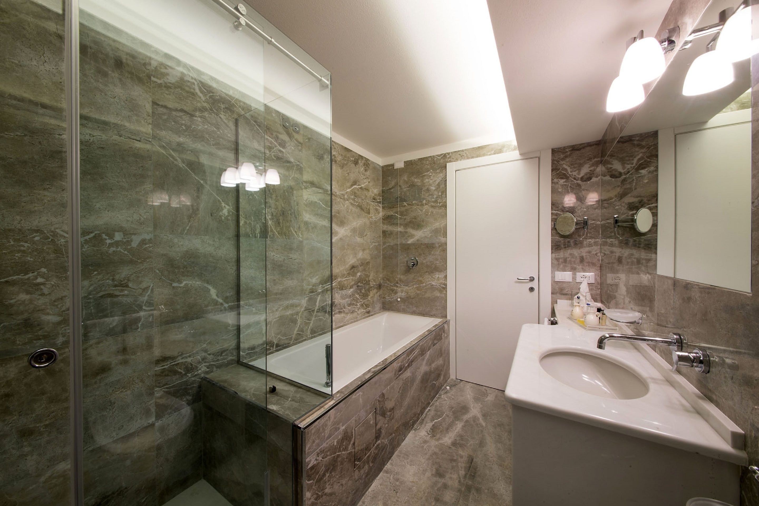 A modern bathroom with a glass-enclosed shower, a freestanding bathtub, and a sink with a mirror.