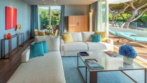 A modern living room with a white sofa, a glass coffee table, and a view of the outdoors. - Gallia Palace Hotel (Castiglione della Pescaia)