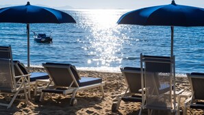 A beach with two blue umbrellas and lounge chairs facing the sea. - Gallia Palace Hotel (Castiglione della Pescaia)