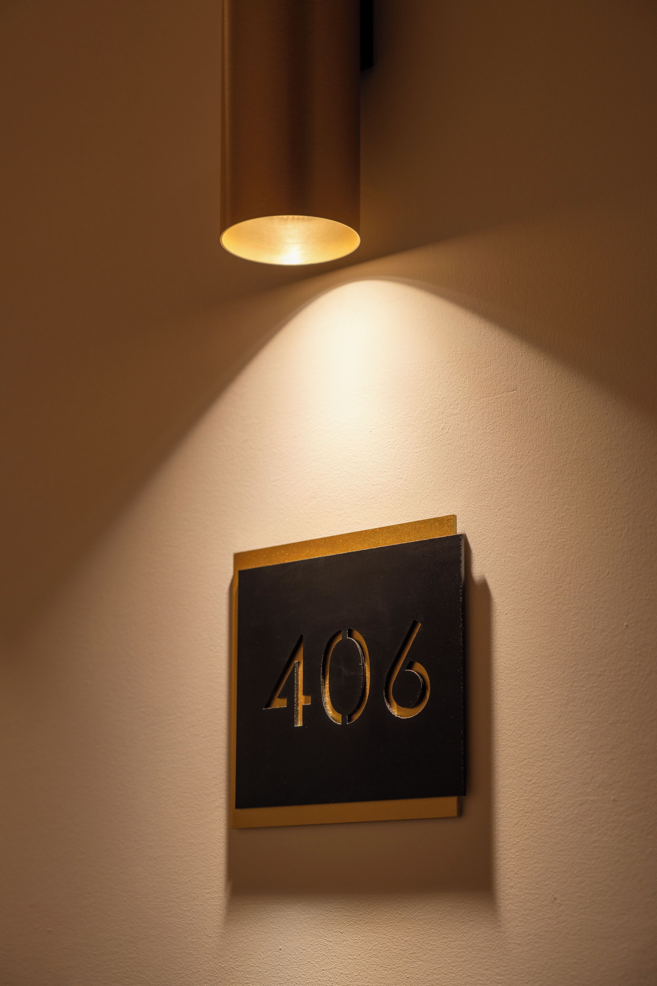 Une plaque avec le numéro 406, fixée au mur et éclairée par un projecteur.