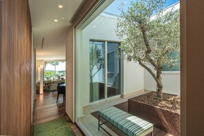 Un intérieur moderne avec un plancher en bois, un banc et une grande fenêtre donnant sur un jardin.
