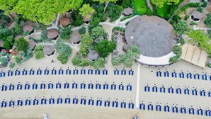 An aerial view of a resort with rows of blue lounge chairs, a circular building, and lush greenery. - Gallia Palace Hotel (Castiglione della Pescaia)