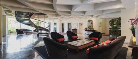 A spacious lobby with a spiral staircase, comfortable seating, and a large mirror.