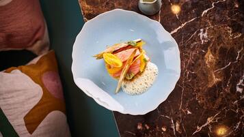 A plate of food on a marble table with a small pitcher of sauce.
