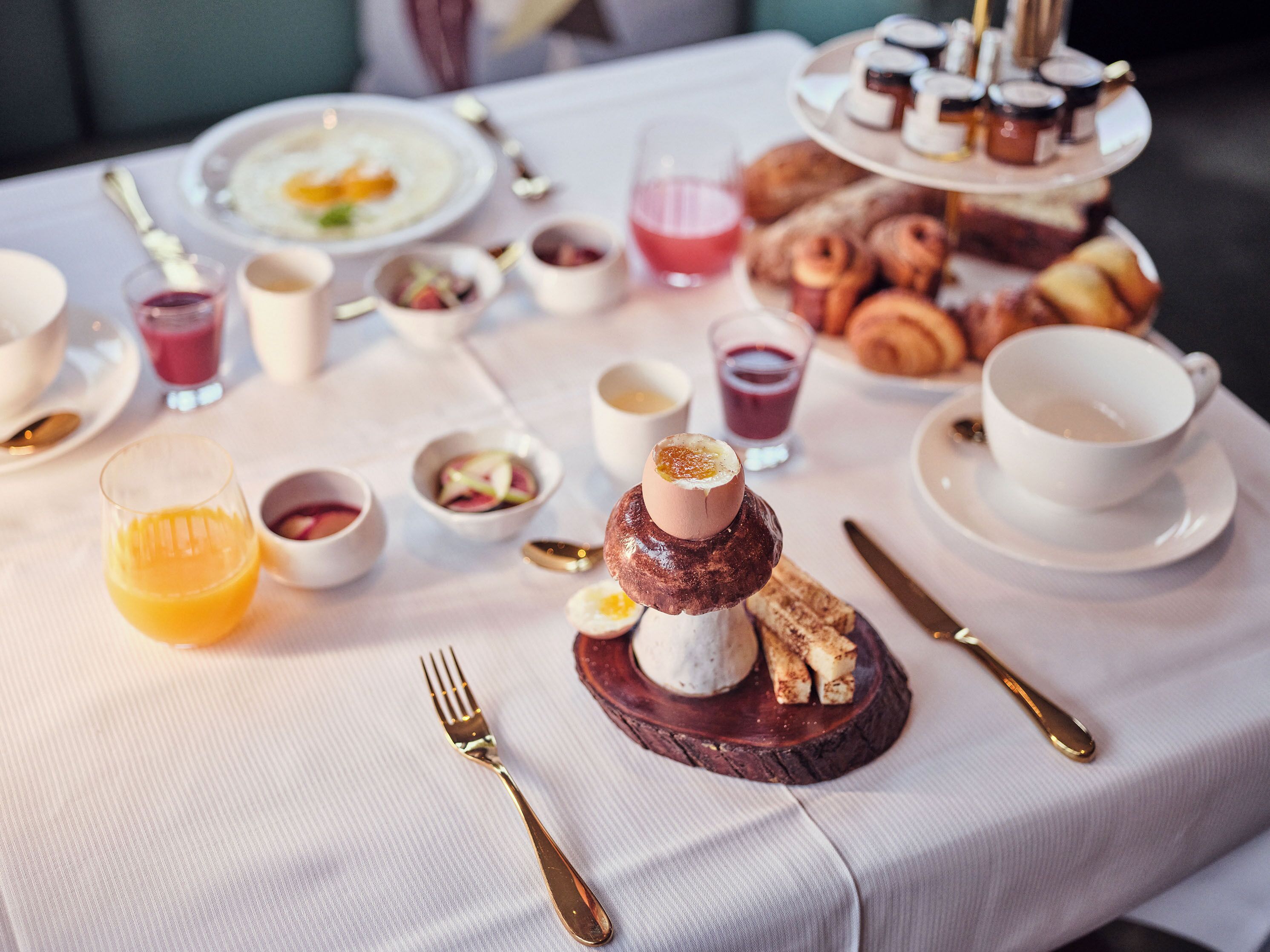 Une table dressée pour le petit-déjeuner, avec une variété d'aliments et de boissons.