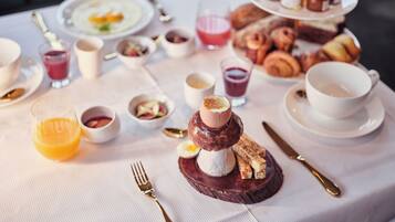 Une table dressée pour le petit-déjeuner, avec une variété d'aliments et de boissons.