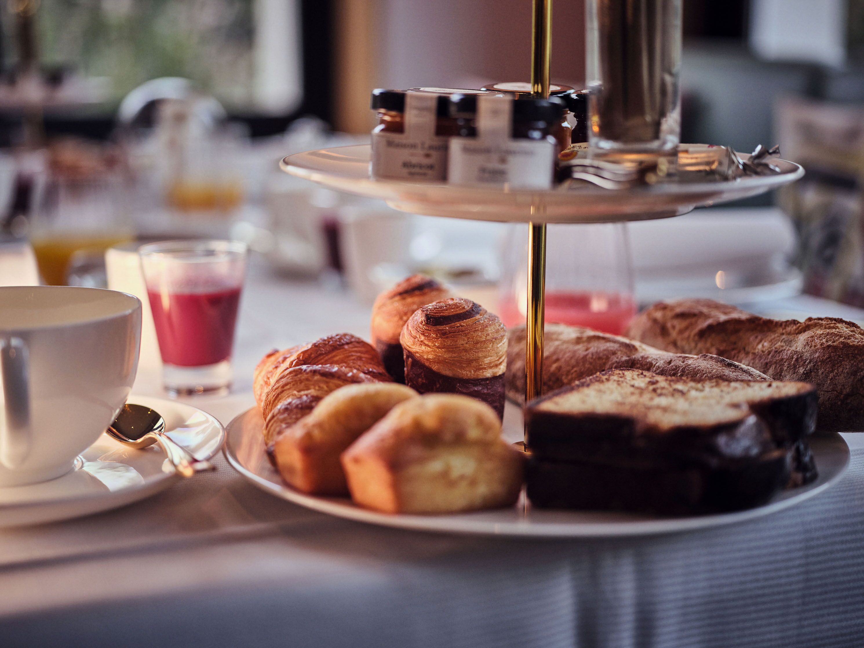 Ein Frühstückstisch mit Croissants, Brot, einer Kaffeetasse und einem Glas Saft.