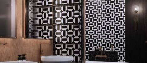 A modern bathroom with two sinks, a large mirror, and a patterned wall.