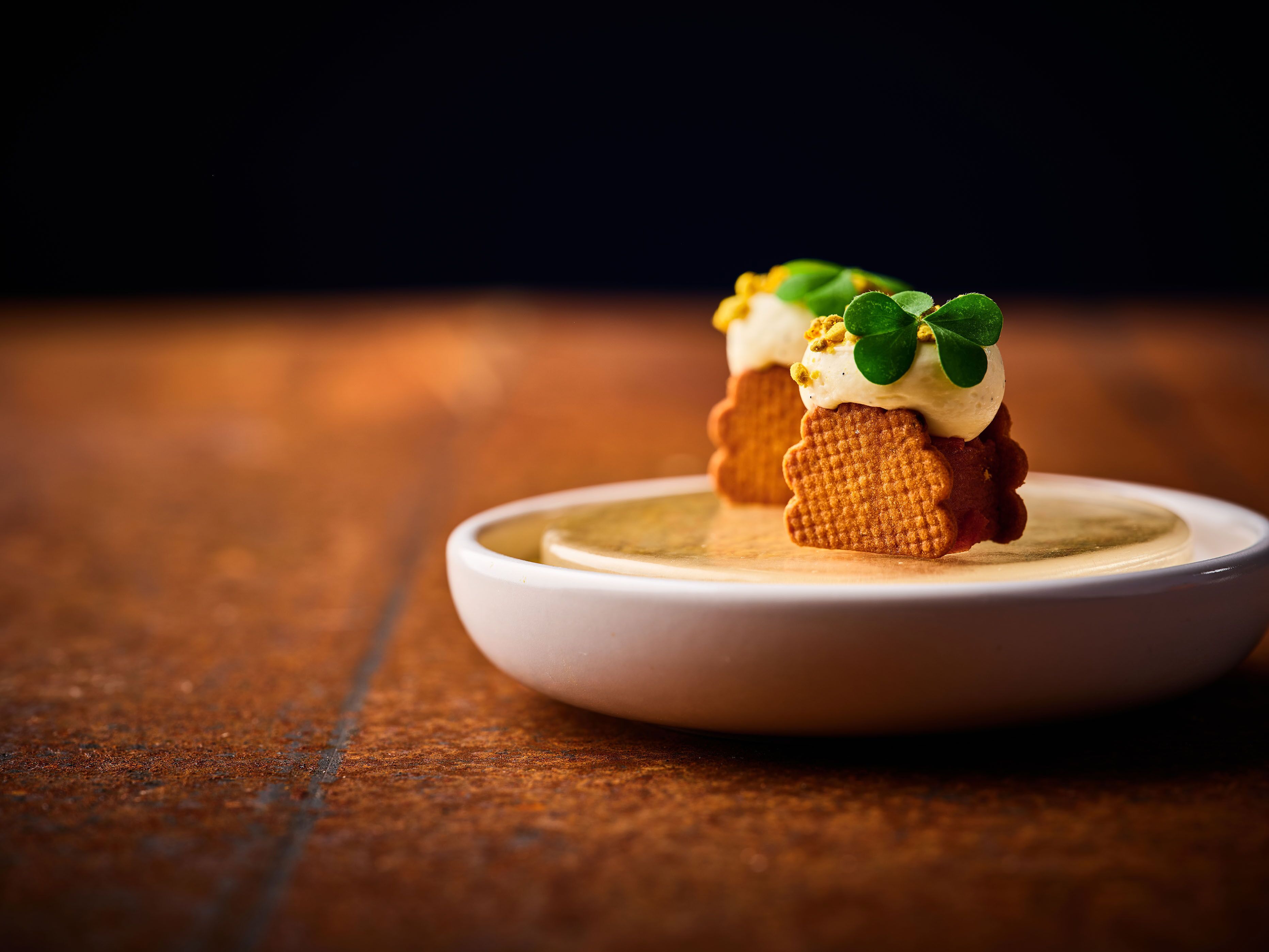 Een nagerecht met een gaufre, slagroom en een groene garnering op een wit bord.