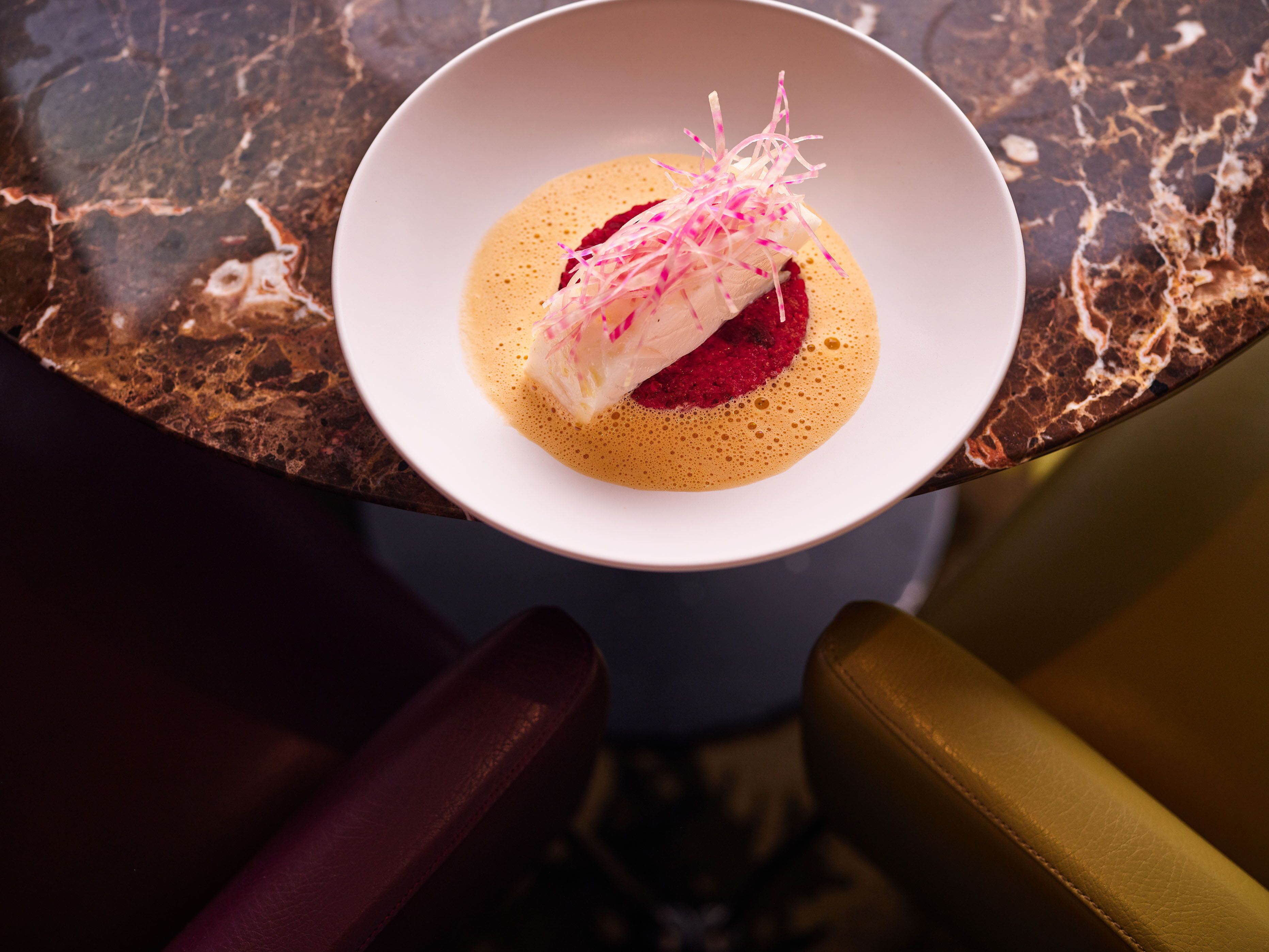 A white bowl with a dessert on a marble countertop.