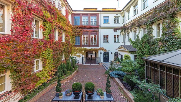 A courtyard with brick flooring, potted plants, and a glass greenhouse. - Stikliai Hotel - Relais & Châteaux (Vilnius)