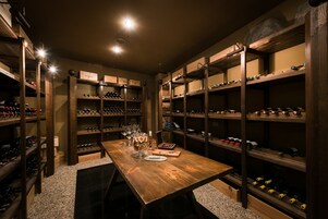 Una bodega con estantes de madera y una mesa con copas de vino y tapones de corcho.