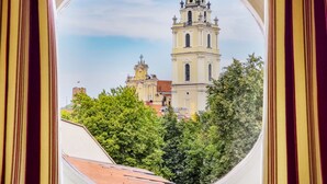 A view through a window of a building with a prominent tower and surrounding greenery. - Stikliai Hotel - Relais & Châteaux (Vilnius)