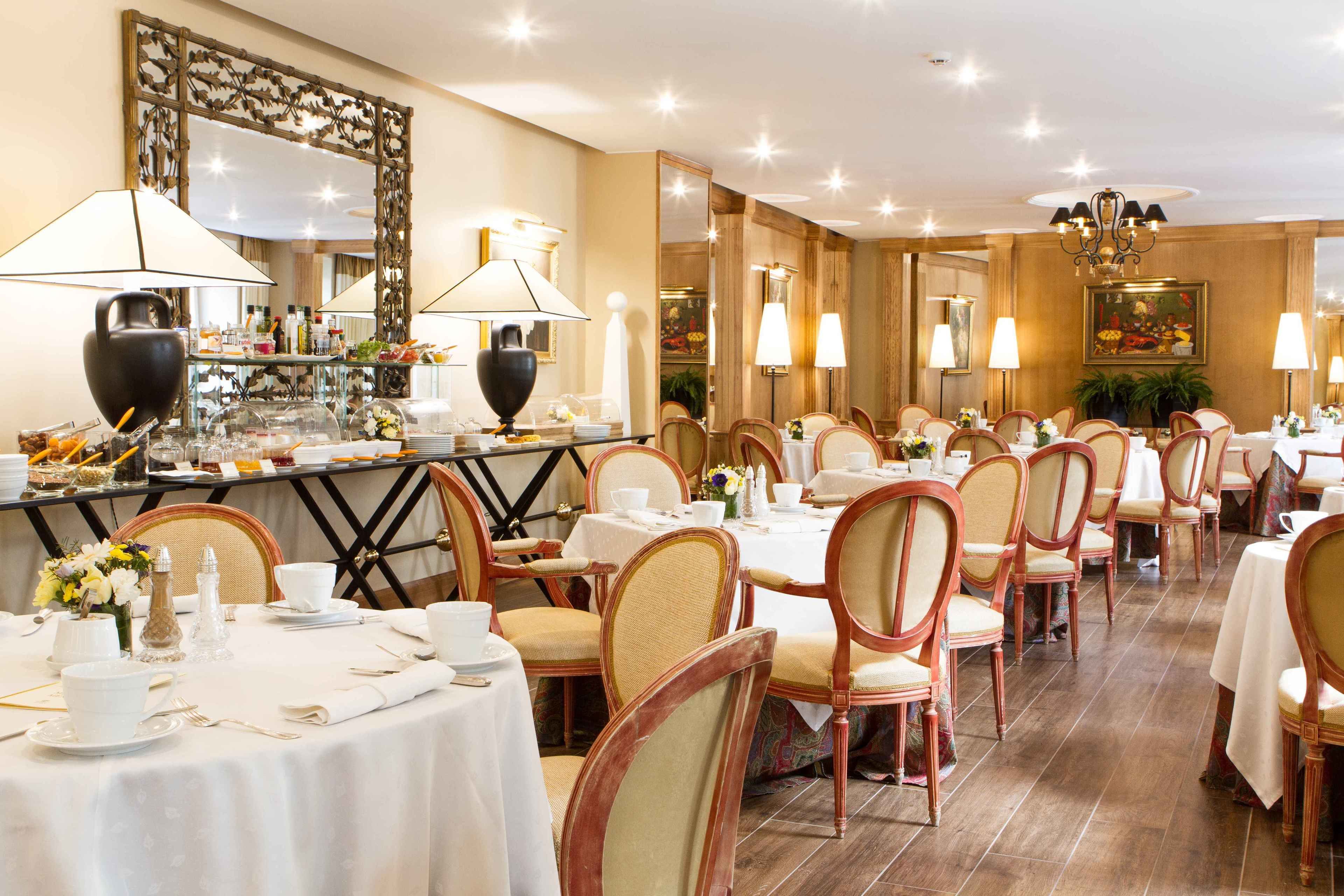 A restaurant with multiple tables and chairs, a bar area with various food items, and decorative lighting.