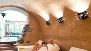 A spa room with a stone wall, a white bathtub, and a person reading a book. - Stikliai Hotel - Relais & Châteaux (Vilnius)