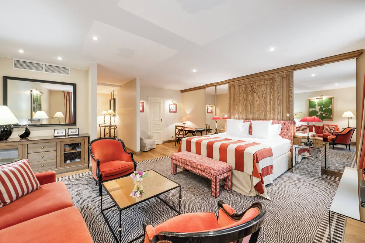 A hotel room with a large bed, a sitting area with a coffee table, a desk, and a chair.