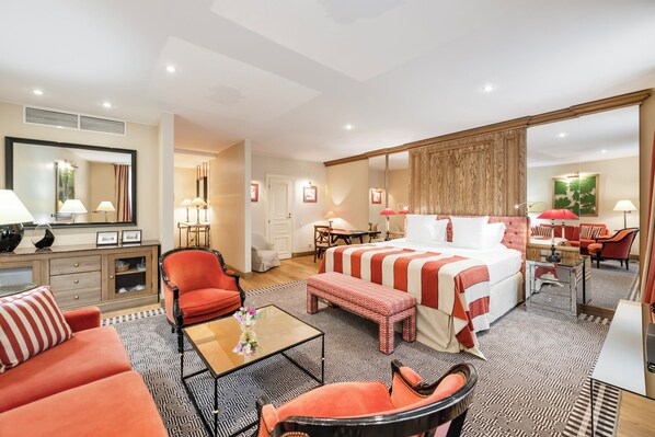 Een hotelkamer met een groot bed, een zithoek met een salontafel, een bureau en een stoel.
