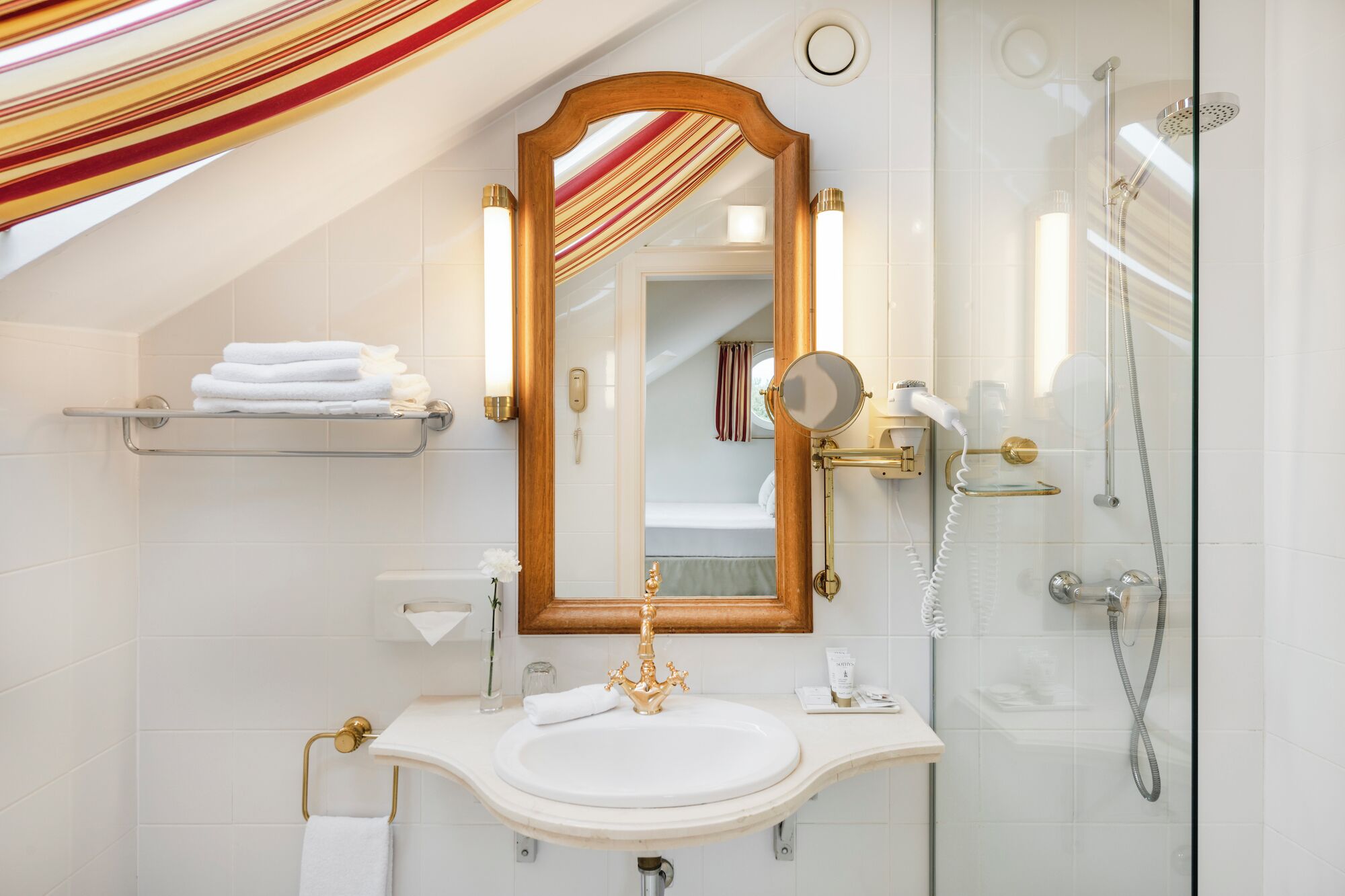 A bathroom with a large mirror, a sink, a shower, and a towel rack.