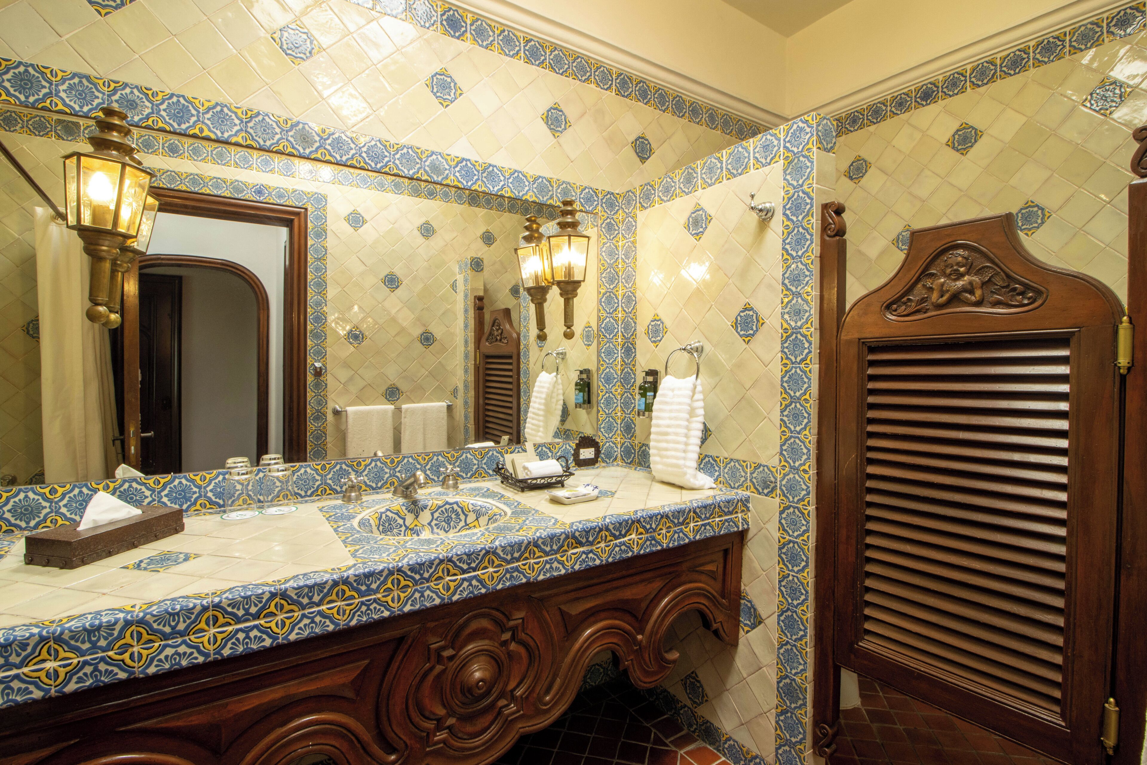 Un baño con salpicadero de azulejos, tocador de madera, espejo y toallero.