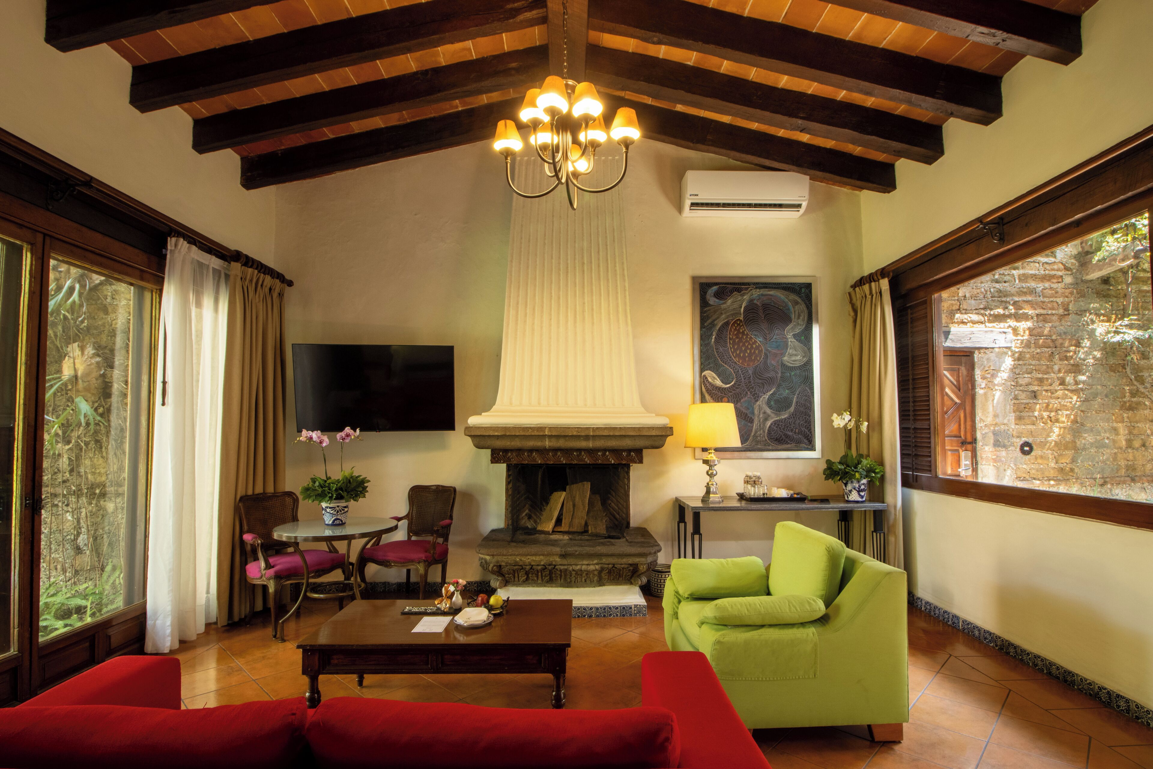Una sala de estar con chimenea, televisor y un sillón verde.