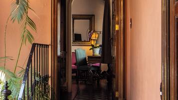 A staircase leading to a room with a chair and a lamp, a mirror on the wall, and a plant.
