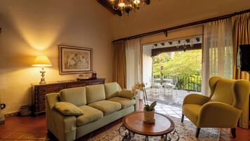 Un salón con sofá, sillón, lámpara y vistas al exterior.