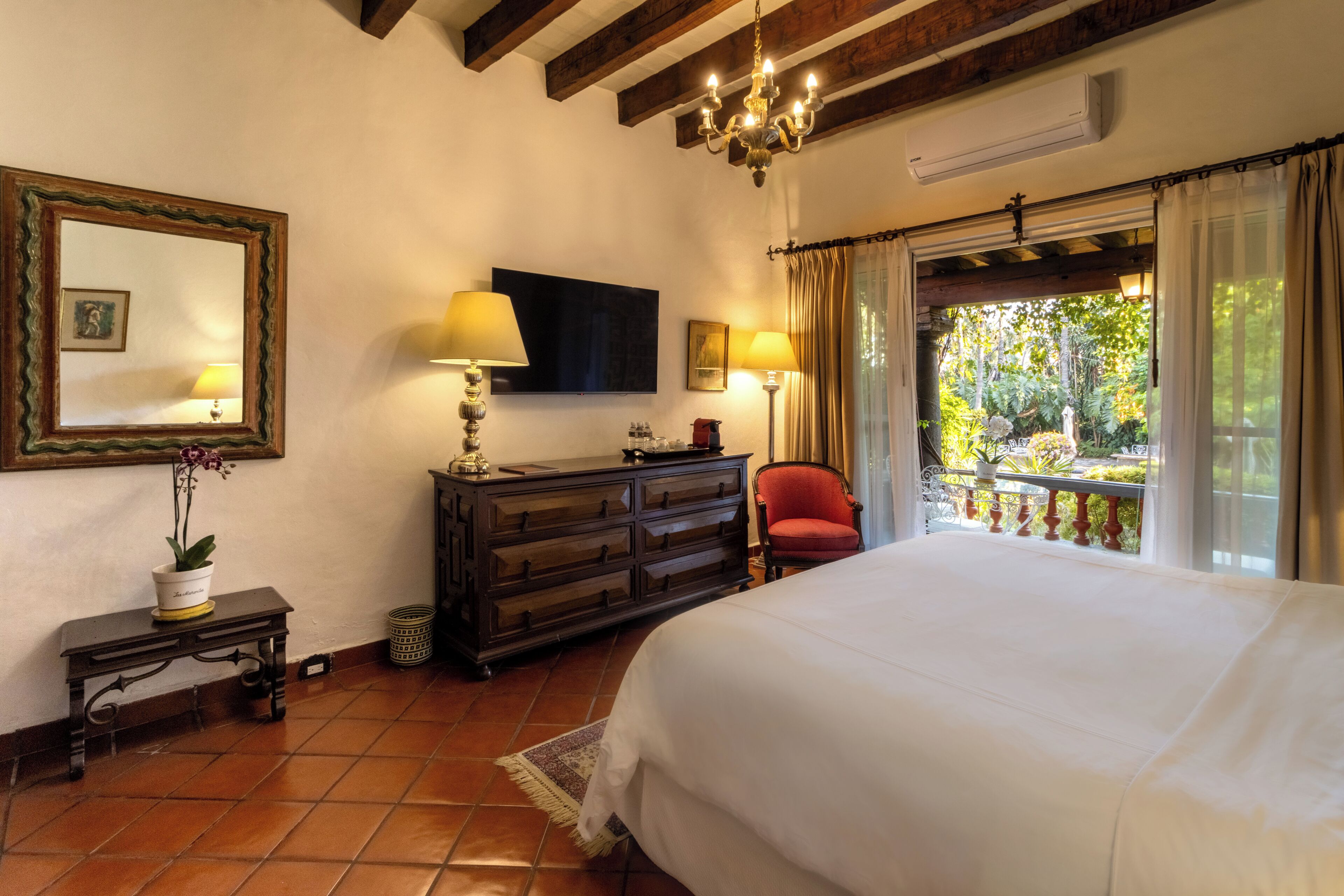 Quarto com cama, penteadeira, espelho e varanda com vista.