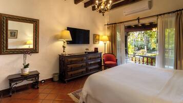Quarto com cama, penteadeira, espelho e varanda com vista.