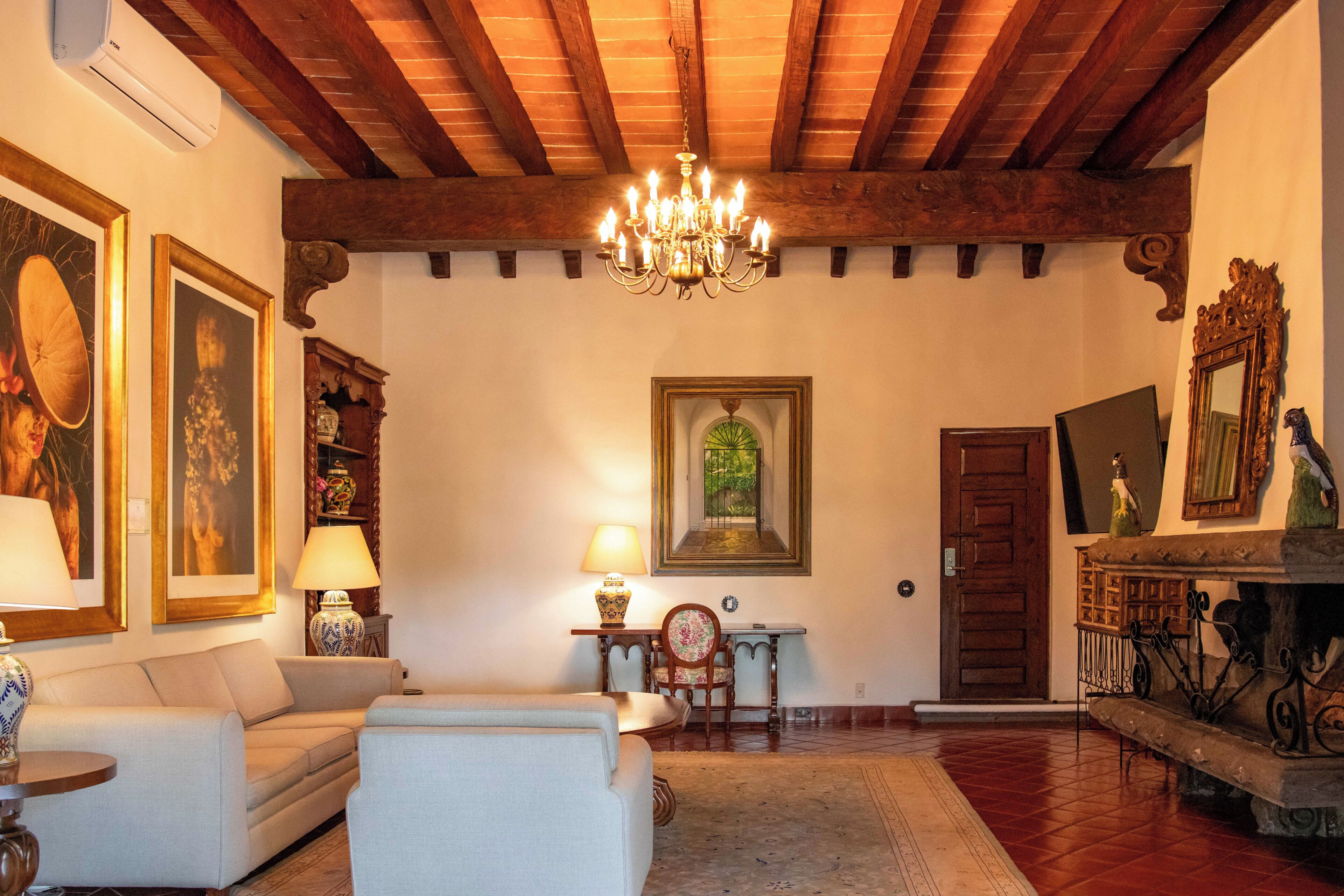 A room with a chandelier, a fireplace, a wooden ceiling, and a door.