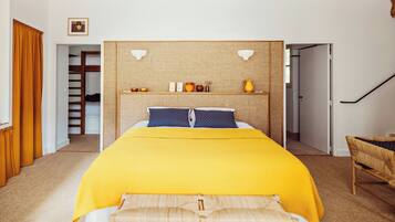 A bedroom with a bed, a headboard with shelves, a picture on the wall, and a staircase.