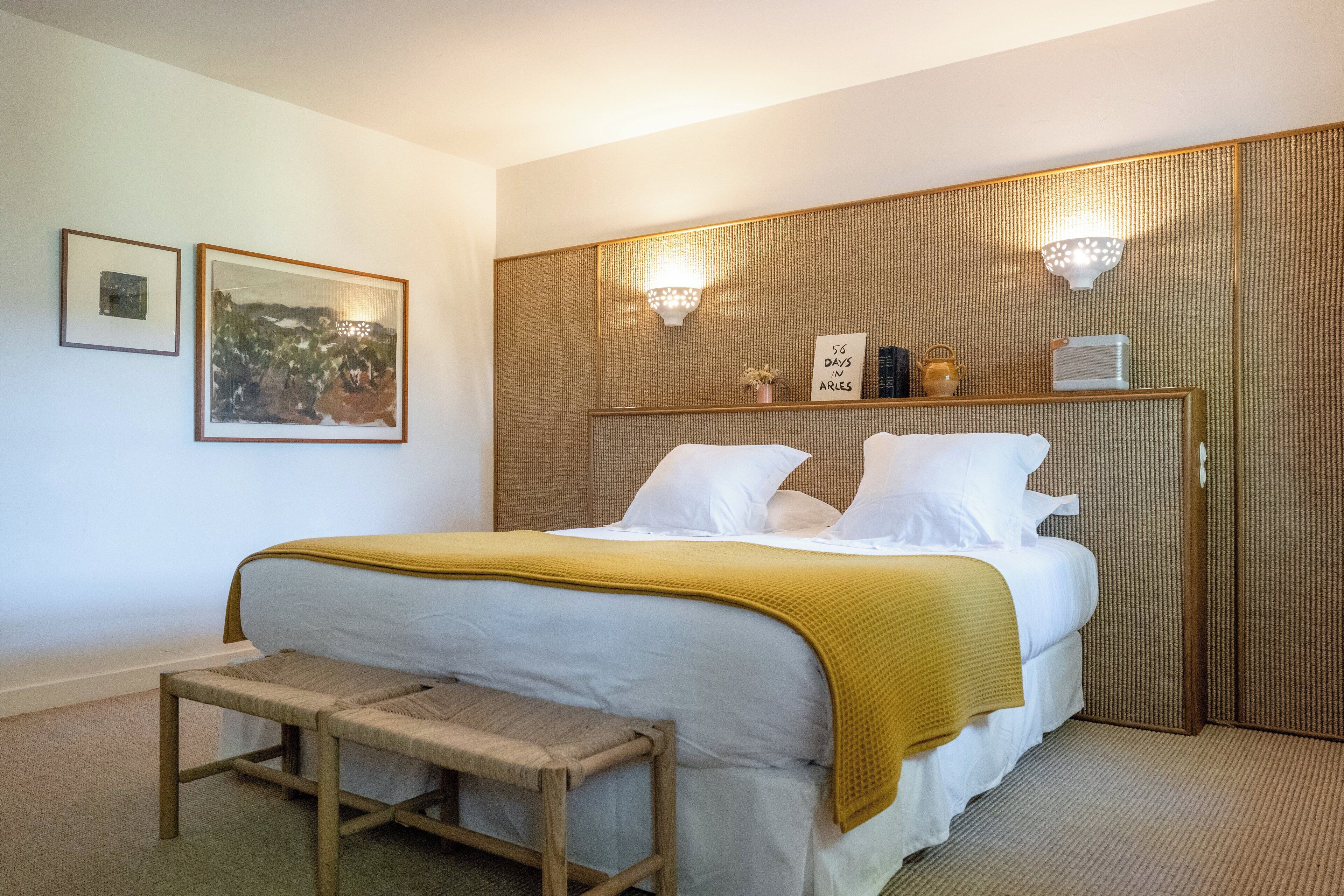 A neatly arranged bedroom with a bed, bedside tables, and wall-mounted lights.