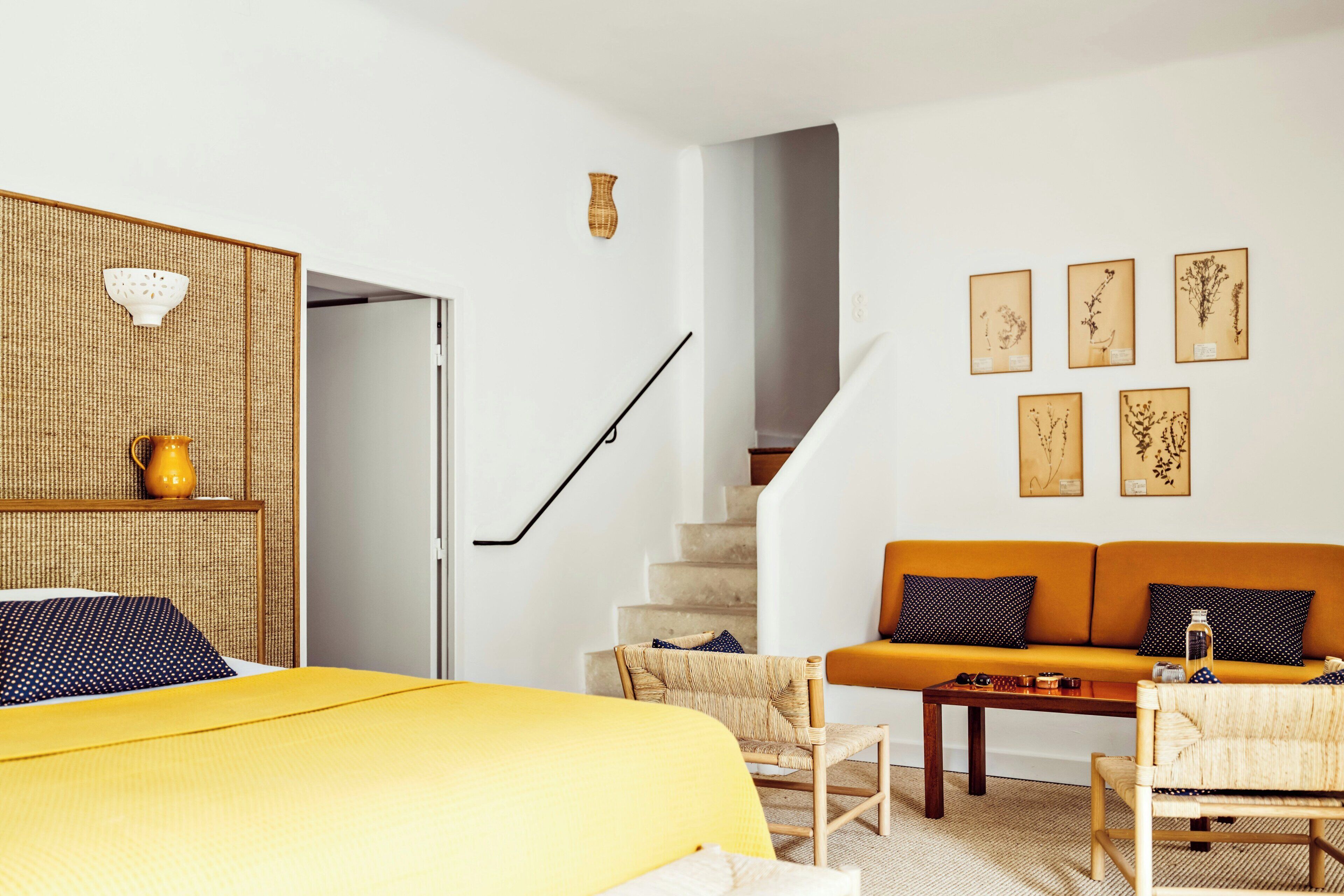 Una habitación con una cama, un sofá, una silla, una escalera y obras de arte colgadas en la pared.