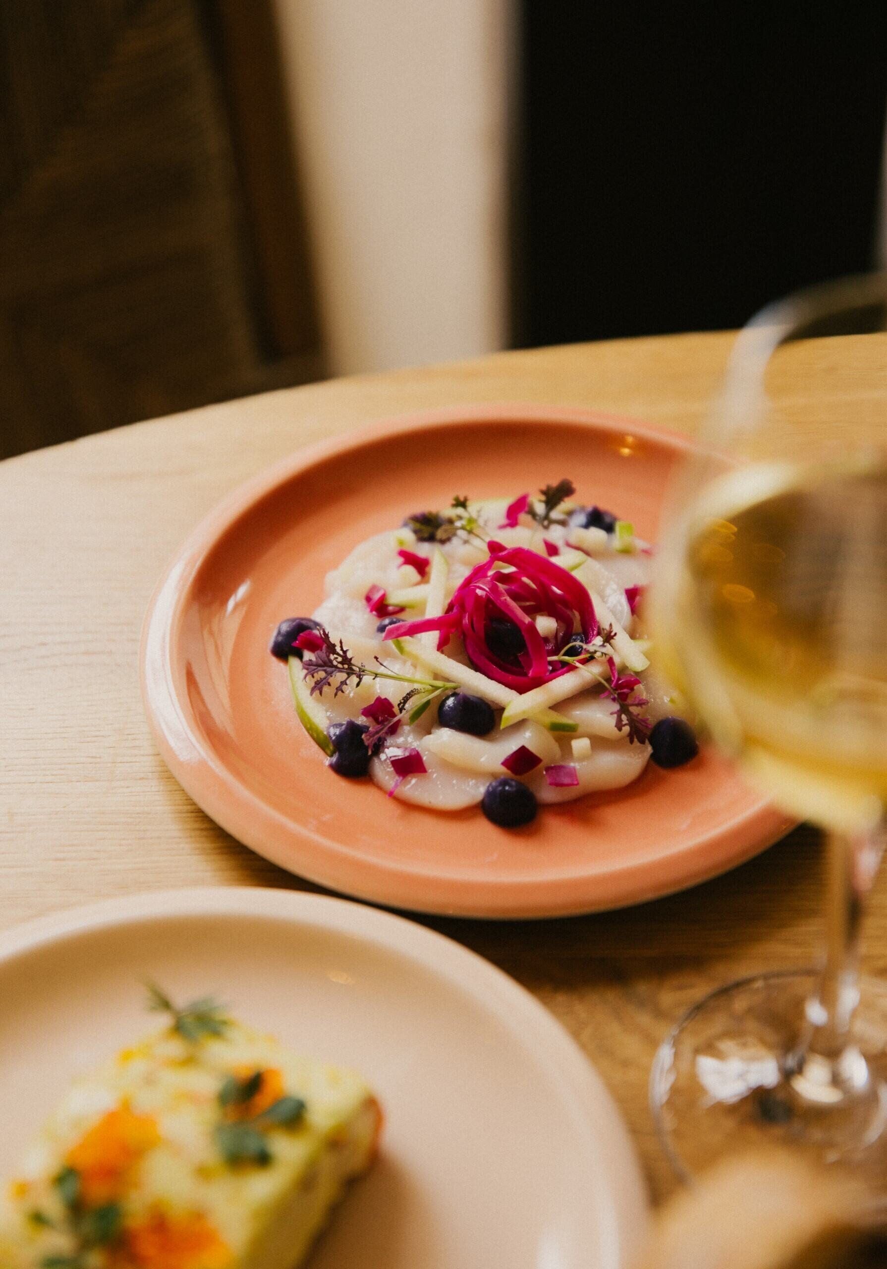A table with a plate of food and a glass of white wine.