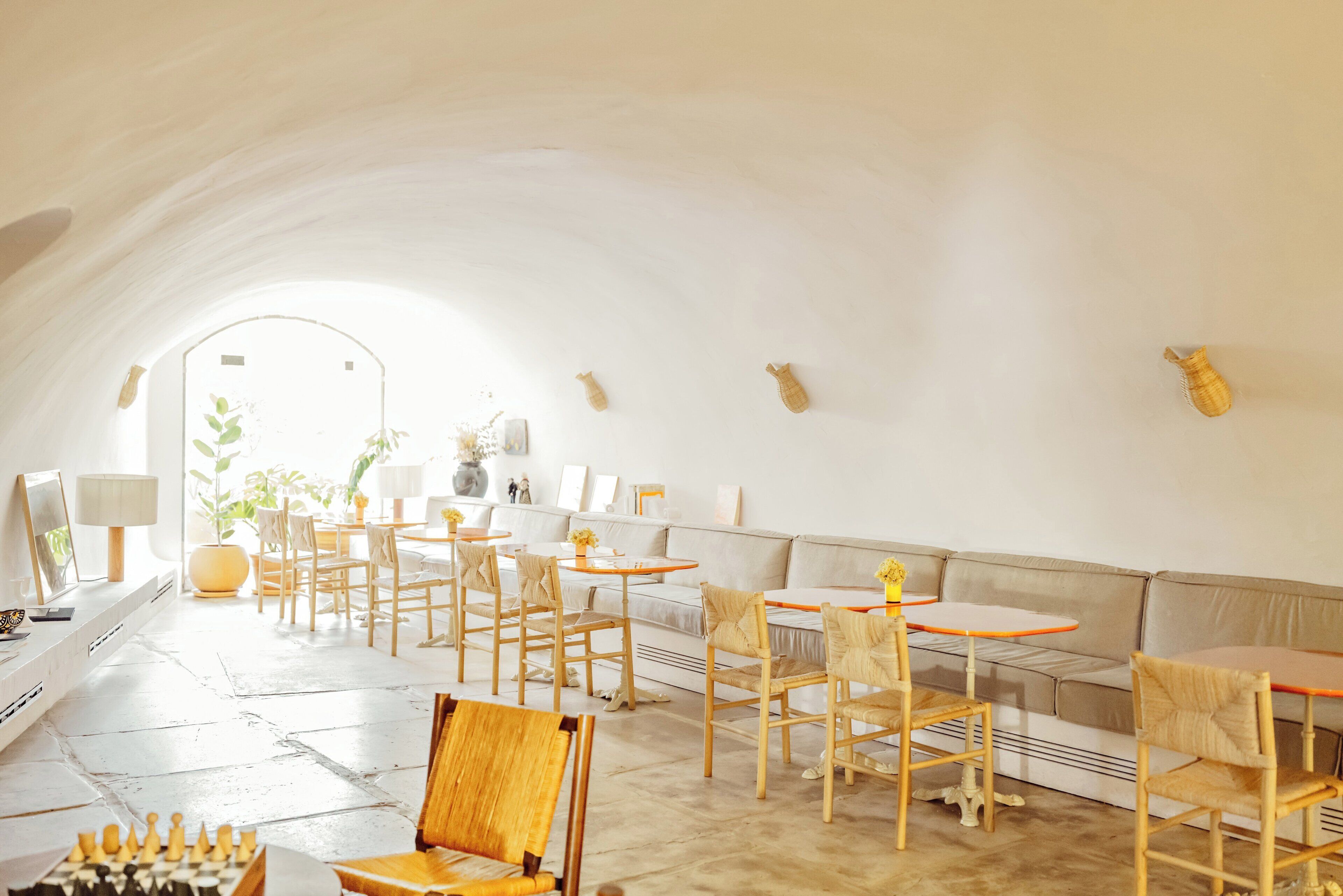 A spacious, well-lit interior with a long dining table, multiple chairs, and a sofa.