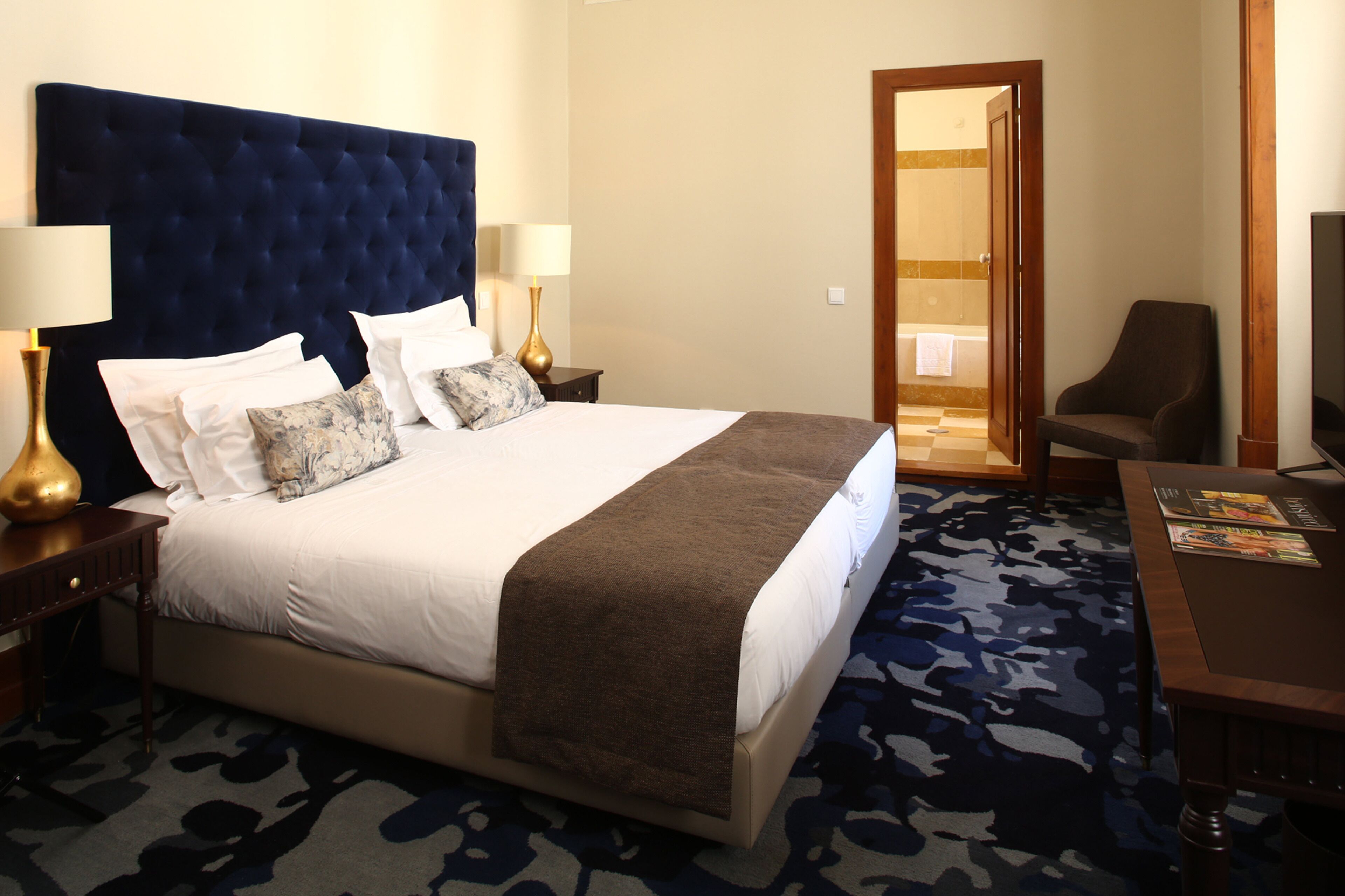 Une chambre d’hôtel avec un grand lit, deux tables de chevet avec des lampes, une chaise et un téléviseur.