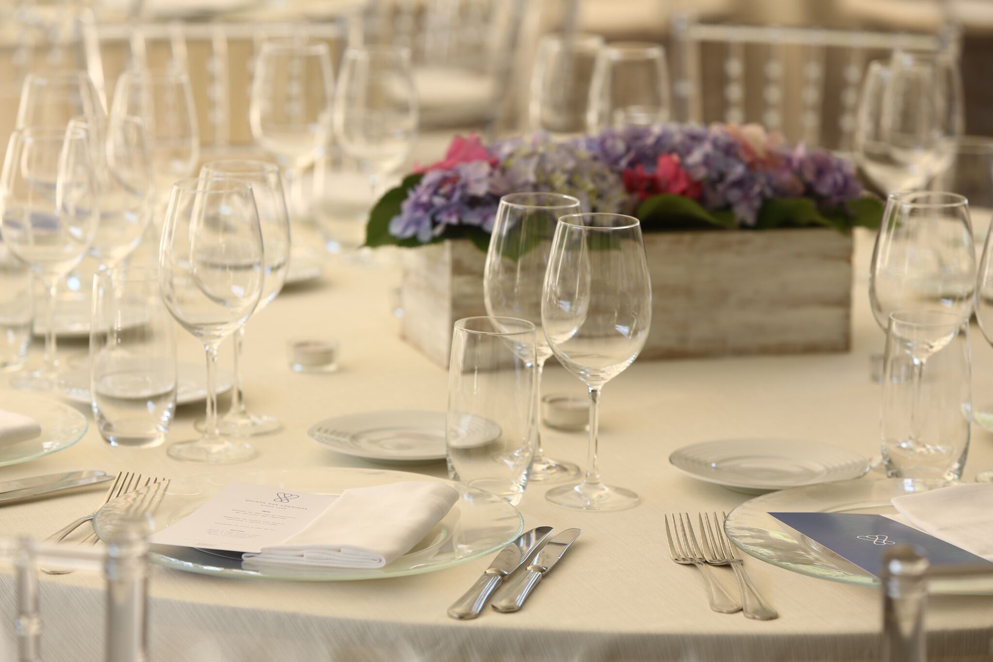 A table set for a formal event with clear glassware, plates, and cutlery.