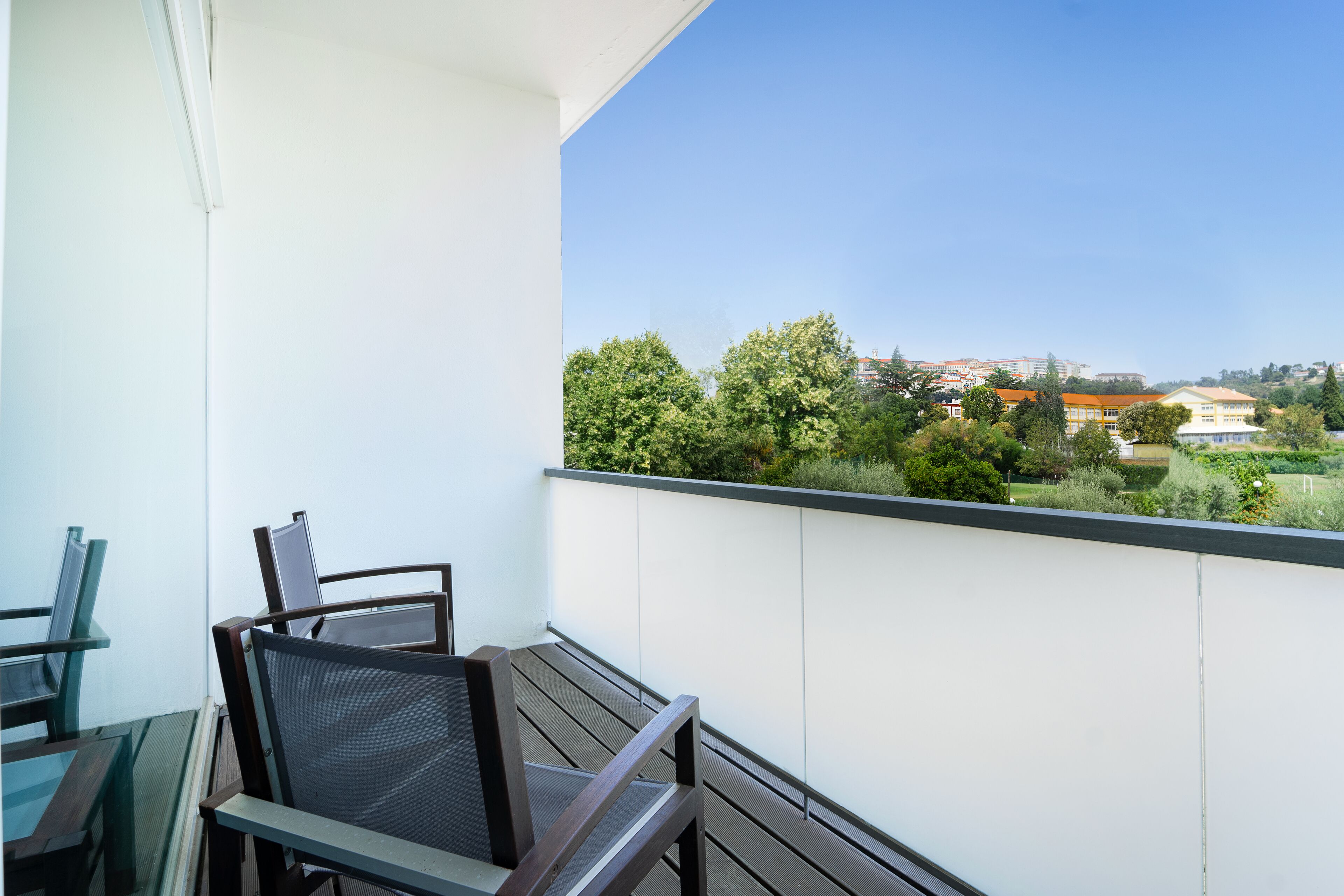 A balcony with a view of greenery and buildings.