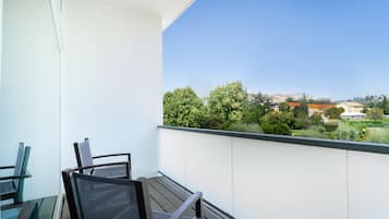 Een balkon met uitzicht op groen en gebouwen.