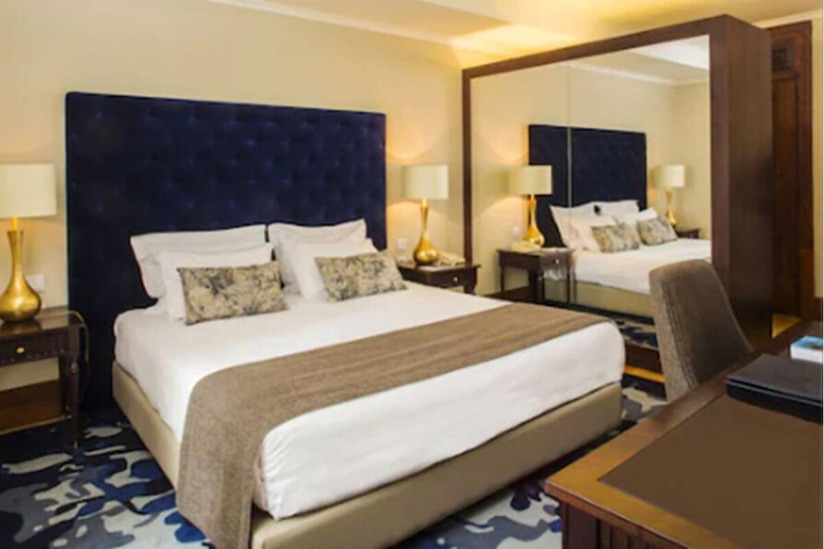 Une chambre d’hôtel avec un grand lit, un bureau, une chaise, une table de chevet et un miroir.