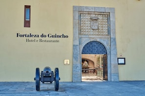 The entrance to Fortaleza do Guincho Hotel e Restaurante, featuring a large arched doorway and a cannon in front.