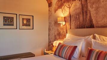 Une chambre à coucher avec un lit, des oreillers, une table de chevet, une lampe et deux œuvres d’art encadrées accrochées au mur.