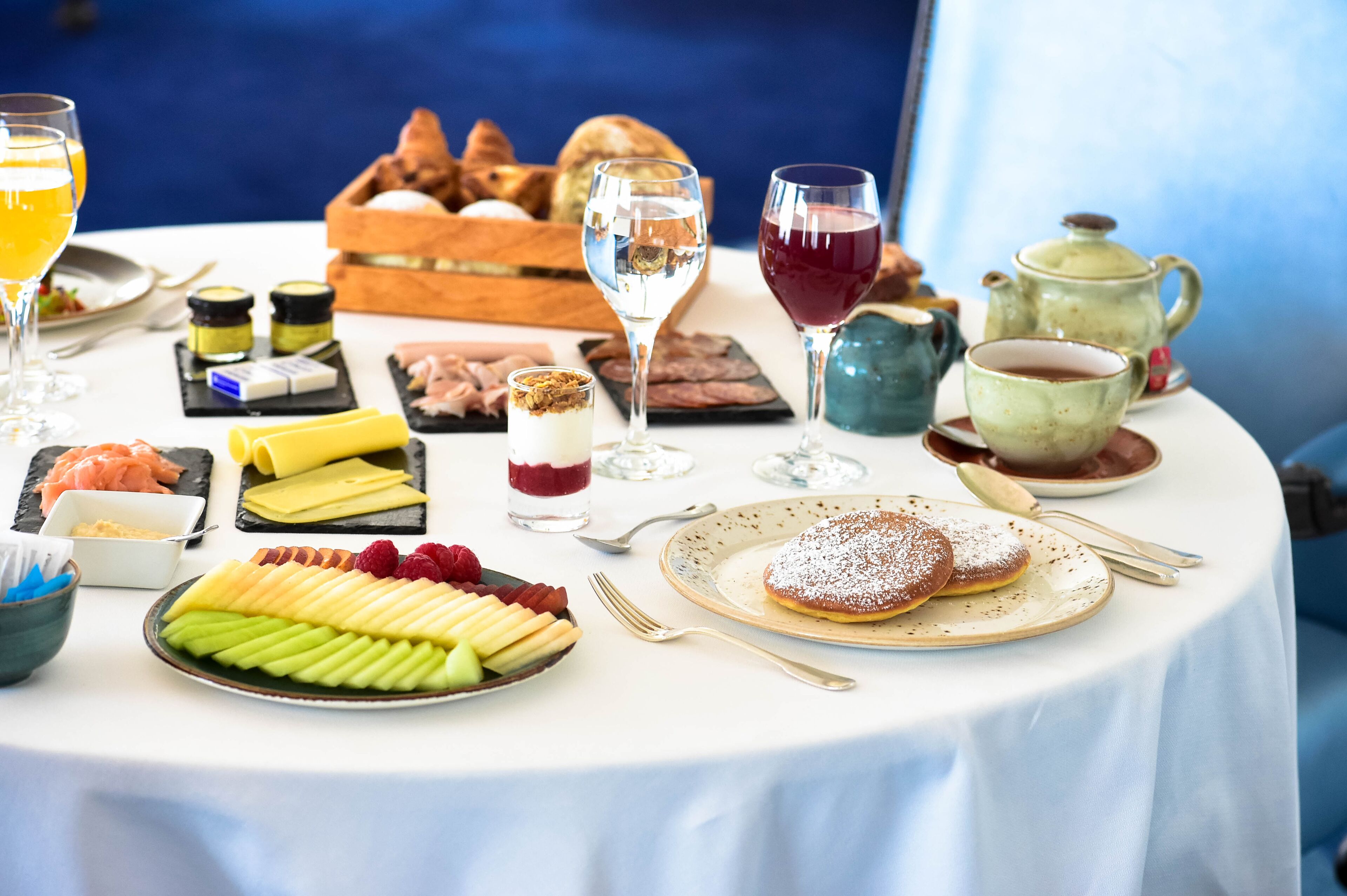 Ein Tisch reichhaltig mit Speisen gedeckt, darunter Gebäck, Obst und Getränke, was auf ein Frühstück oder Brunch hindeutet.