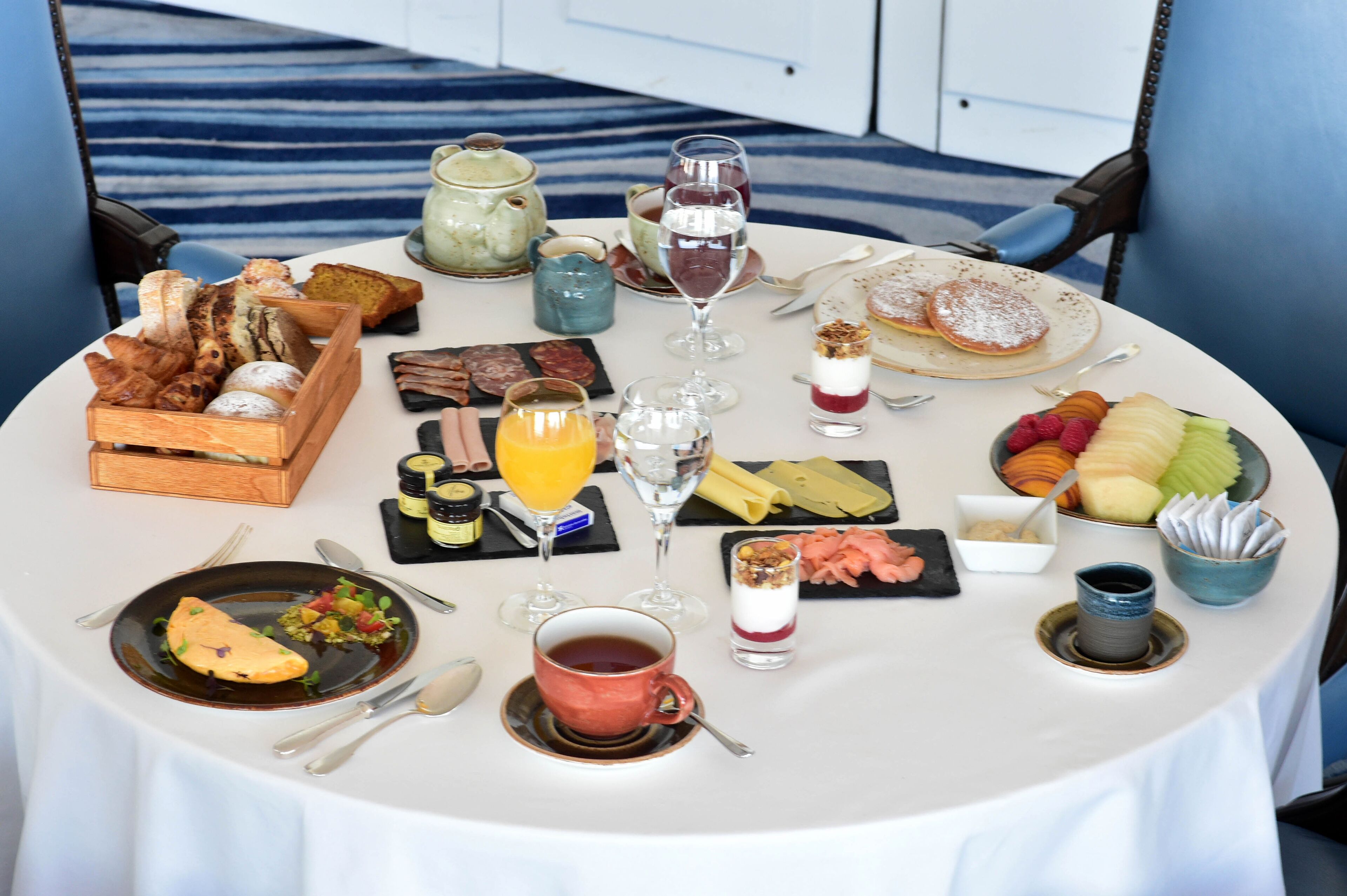 A breakfast table with various foods, drinks, and a teapot.