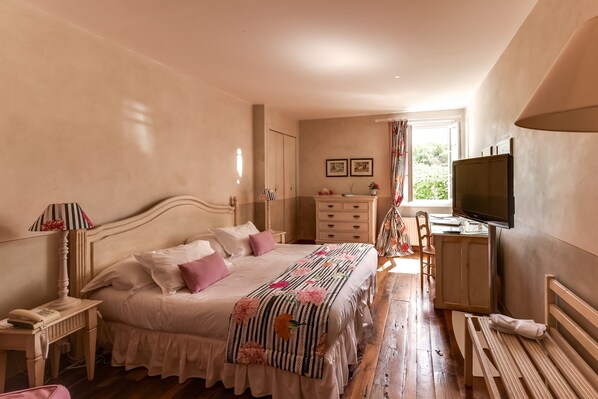 Un dormitorio con una cama grande, mesitas de noche, un televisor y un banco de madera.