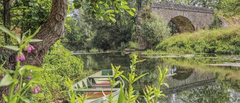 Un río tranquilo con un puente de piedra y barcas.